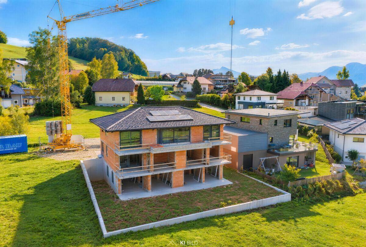 Neubauprojekt im Rohbau mit sichtbaren Ziegelwänden, Balkonen und einem Baukran in ländlicher Umgebung.
