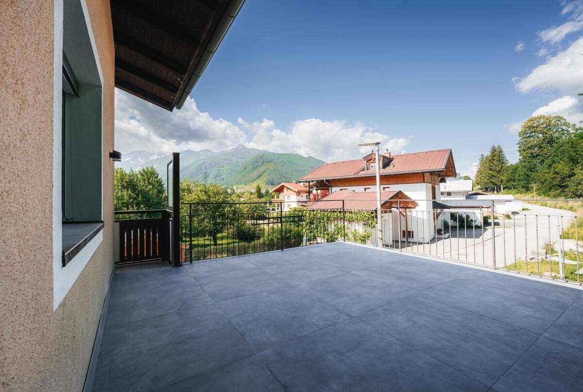 Große, sonnige Terrasse mit Fliesenboden und weitem Blick auf die umliegende Berglandschaft.