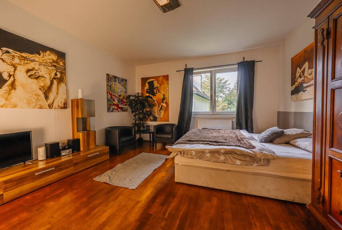 Geräumiges Schlafzimmer mit dunklem Holzboden, großem Bett und künstlerischen Wandbildern.