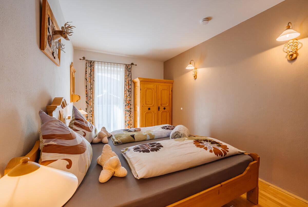 Helles Schlafzimmer mit zwei Einzelbetten, Holzmöbeln und einem Fenster.