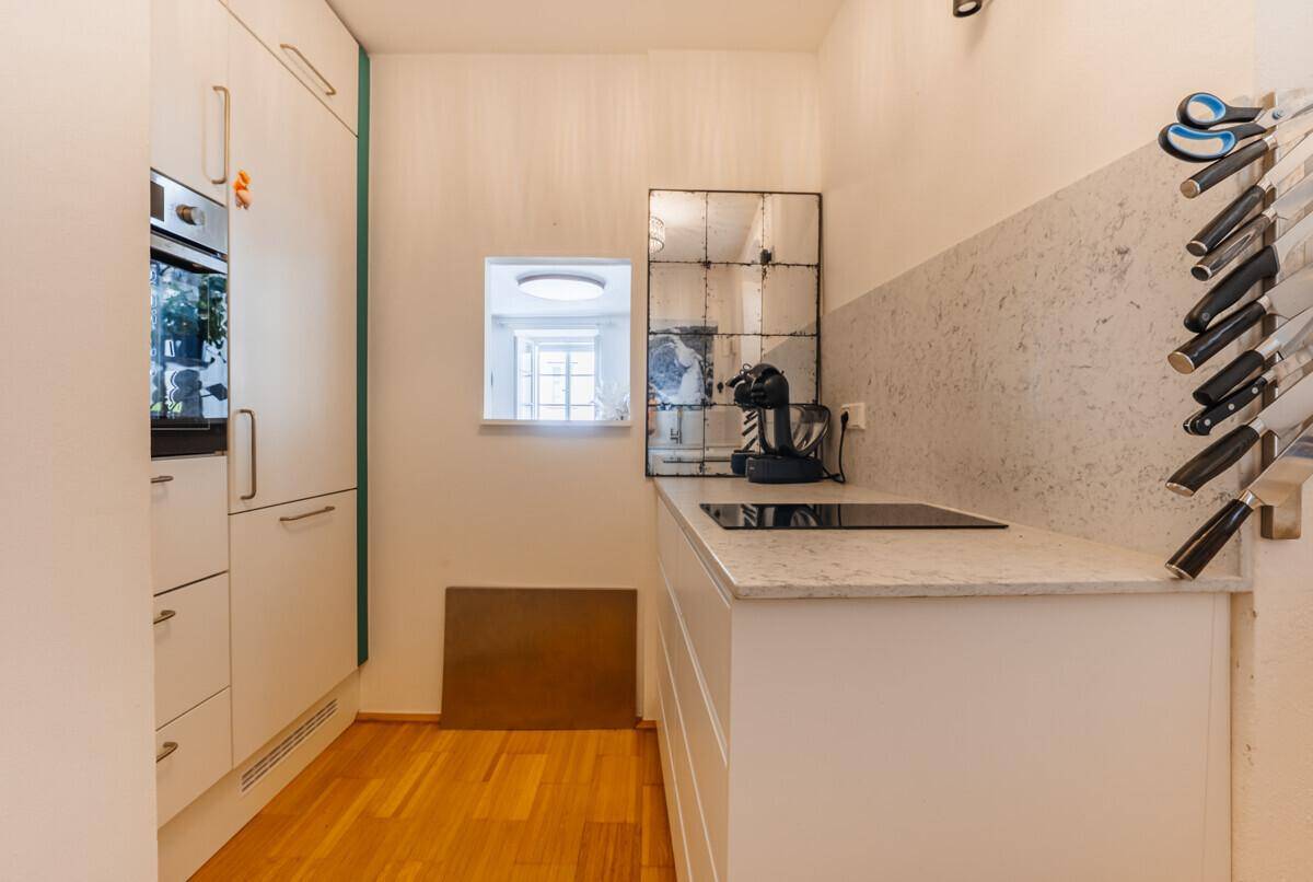 Moderne kleine Küche mit weißen Schränken, Induktionskochfeld und Einbauofen.