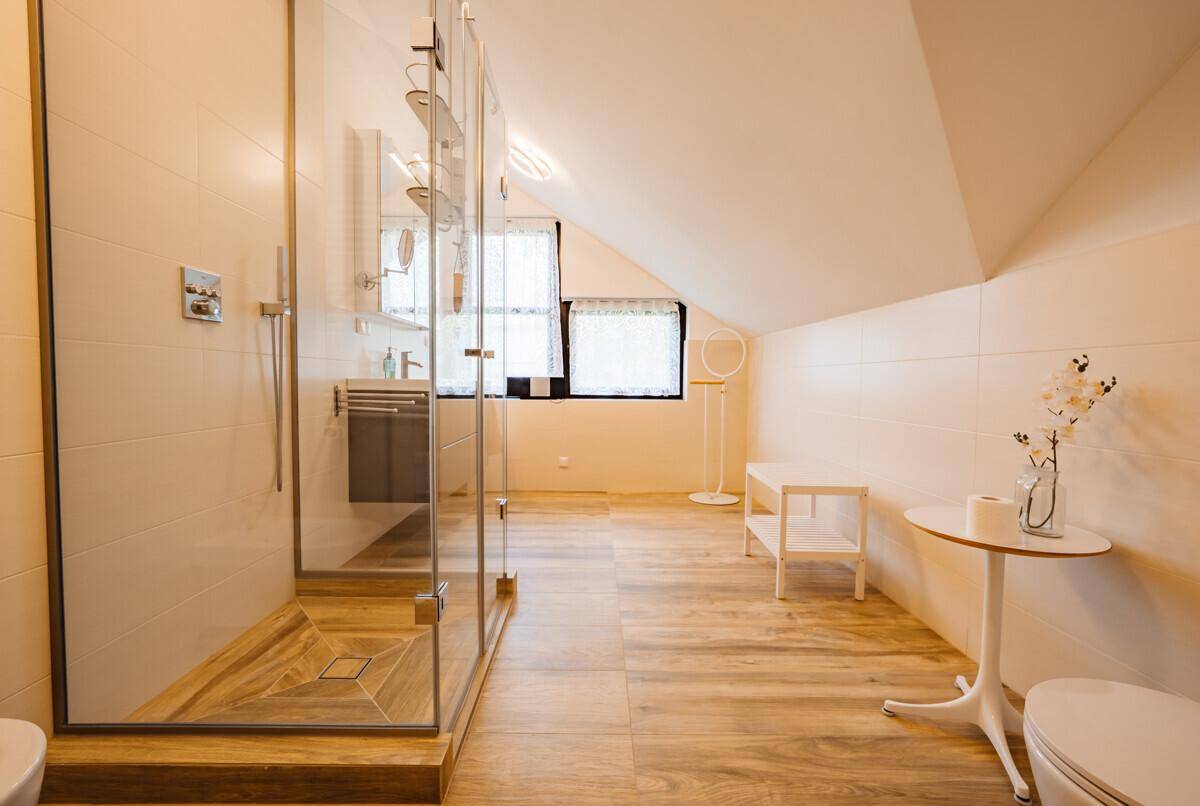 Modernes Badezimmer mit begehbarer Dusche, Holzoptikfliesen und Dachschräge.