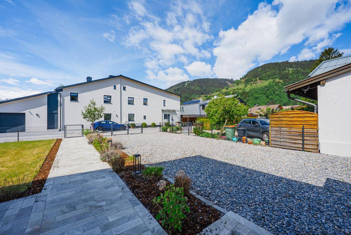 Kiesauffahrt und Parkplatz vor dem Haus mit Blick auf die grünen Berge.