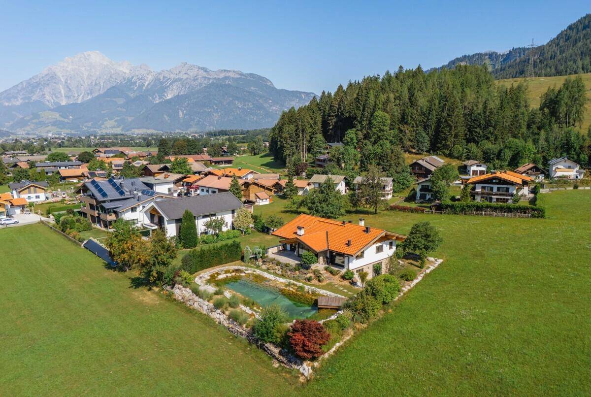 Weitläufige Luftaufnahme des Anwesens mit Nachbarschaft und majestätischer Berglandschaft.