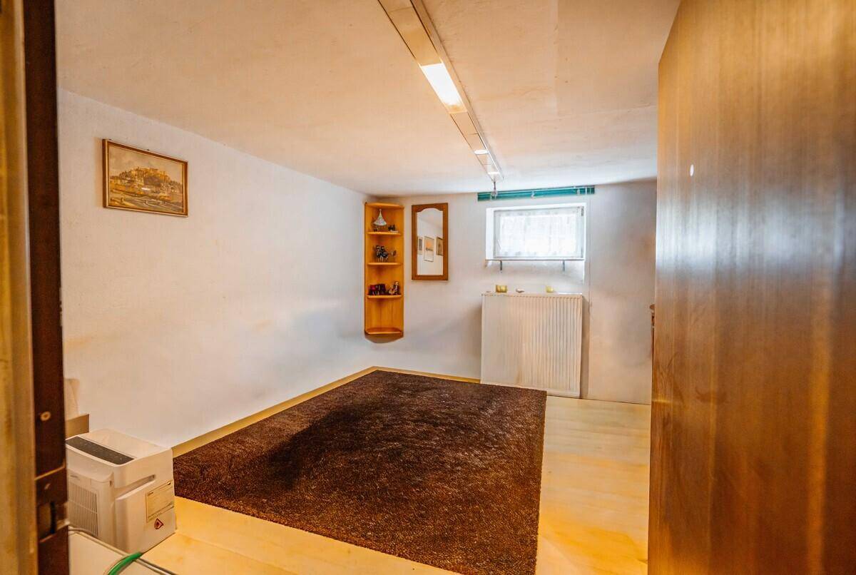 Heller Kellerraum mit Laminatboden, einem Fenster und einfacher Einrichtung.
