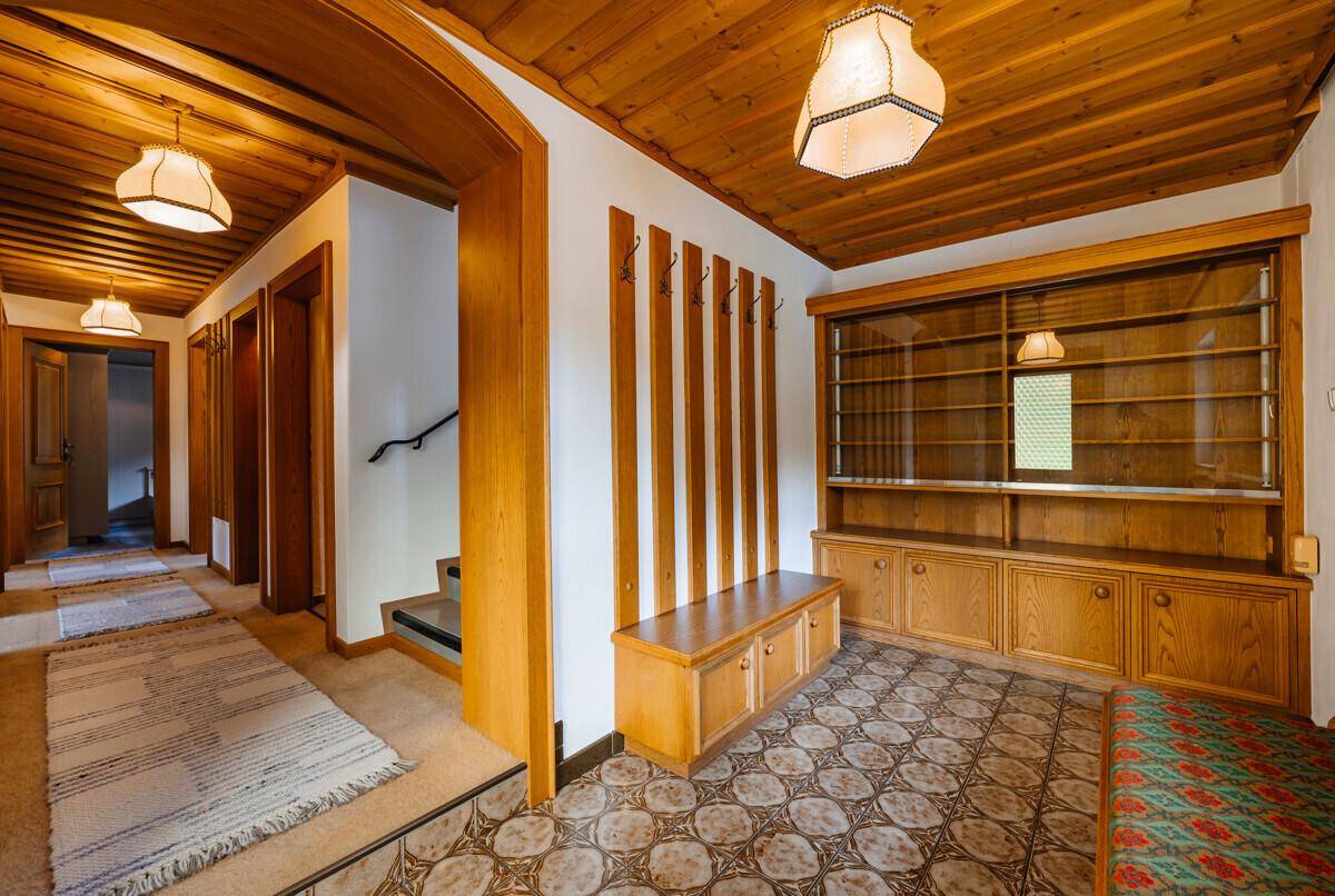 Geräumiger Eingangsbereich mit gemustertem Fliesenboden, Holzdecke und integrierten Holzschränken.