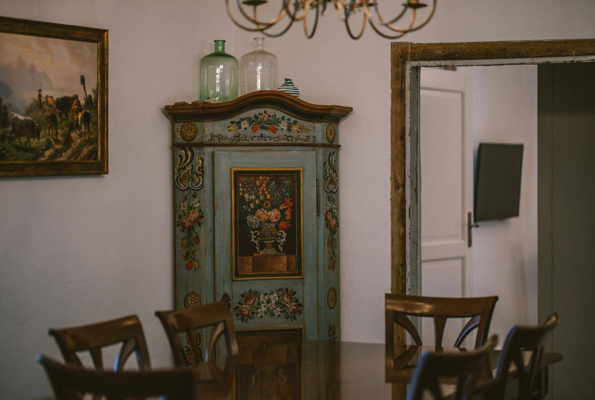 Essbereich mit handbemaltem Schrank, Holztisch und traditionellen Stühlen.