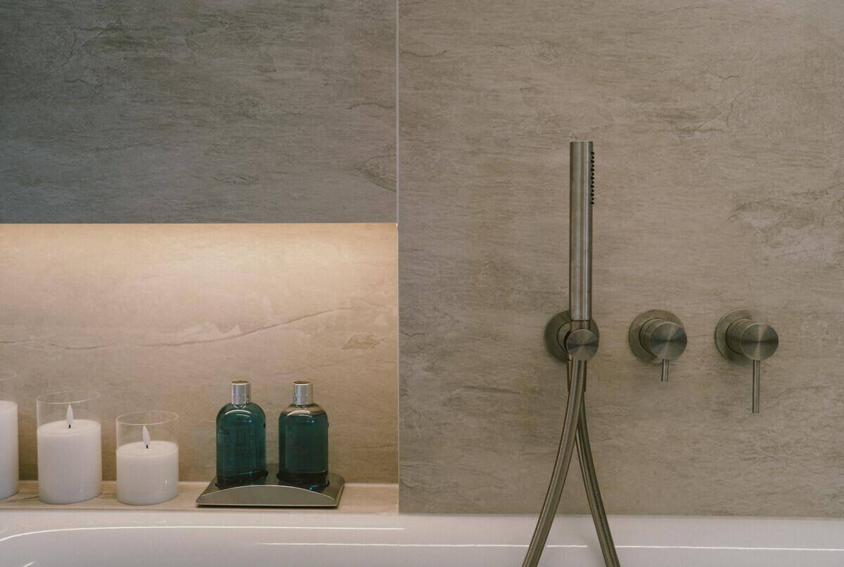 Detailaufnahme der Badewanne mit modernen Armaturen und dekorativen Kerzen.