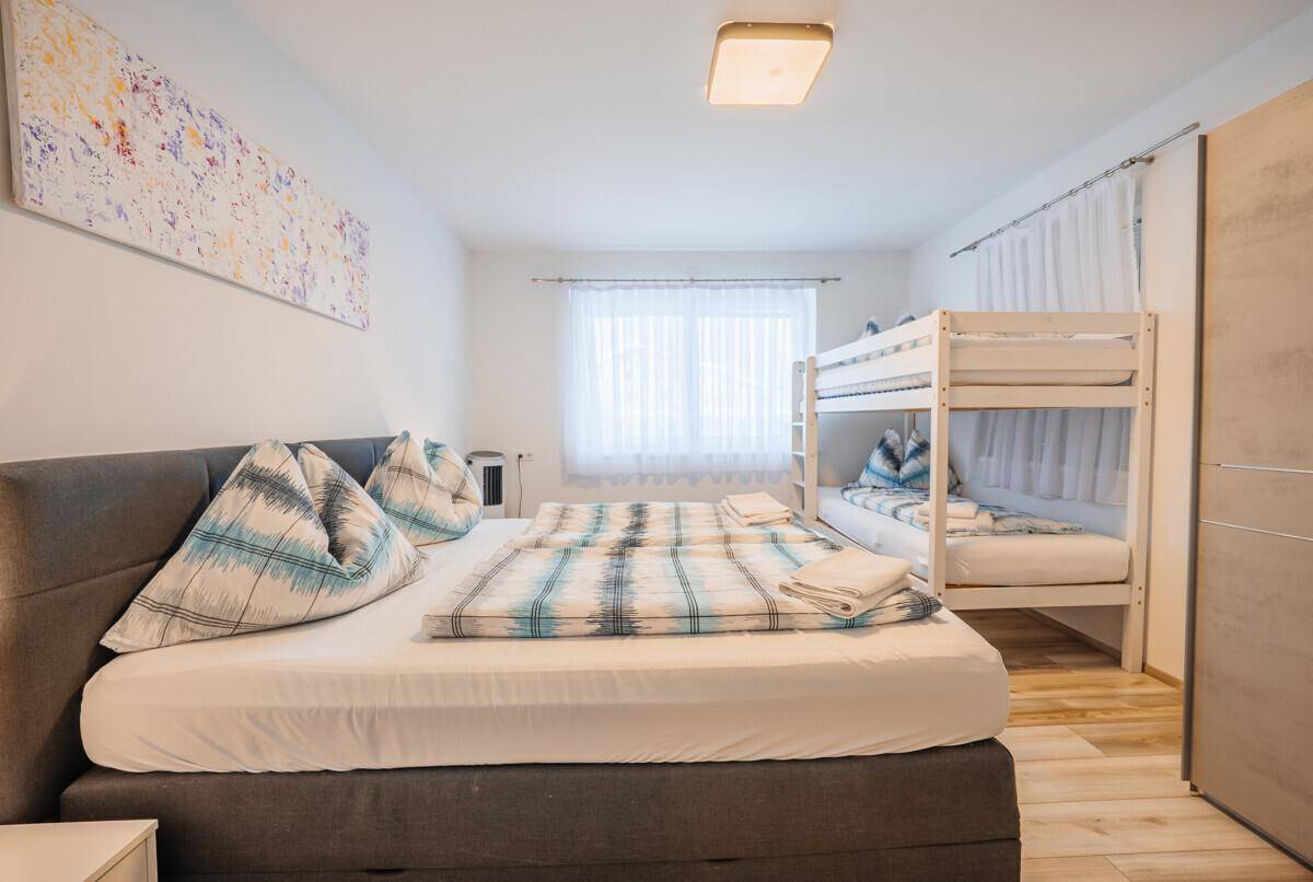 Geräumiges Schlafzimmer mit Doppelbett und Etagenbett, ideal für Familien.