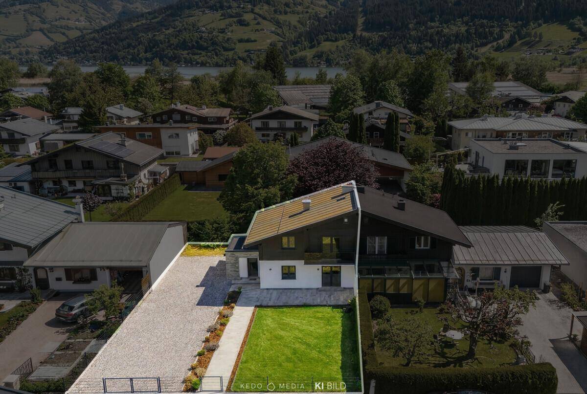 Luftaufnahme eines Hauses mit Grundstücksgrenzen, umgeben von Natur und Bergen.