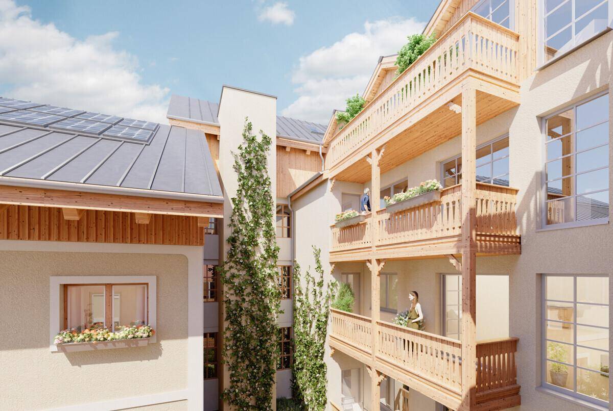 Detailansicht einer Gebäudefassade mit Holzbalkonen, Kletterpflanzen und Solarpaneelen auf dem Dach.