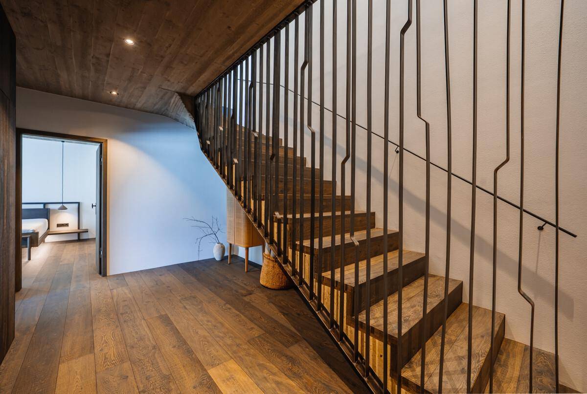 Moderner Flur mit Holztreppe, Metallgeländer und Holzboden.