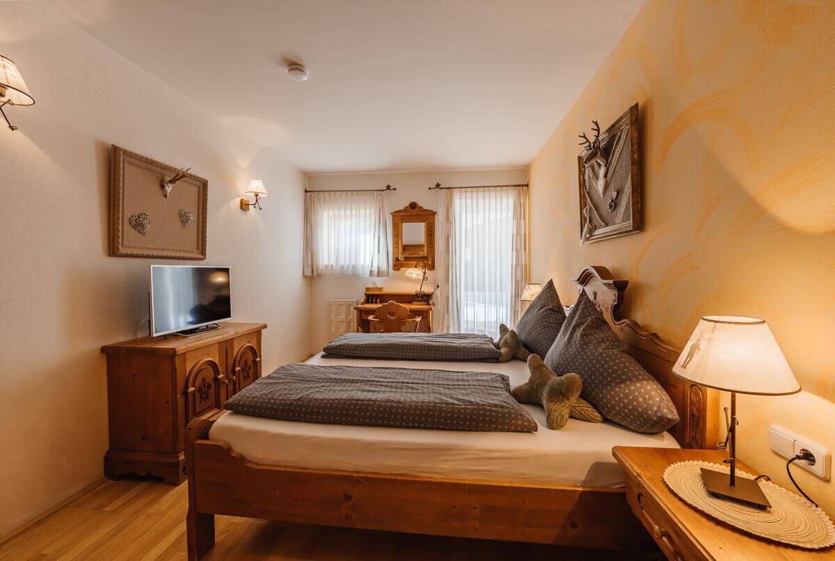 Gemütliches Schlafzimmer mit zwei Einzelbetten, Holzmöbeln und traditioneller Dekoration.