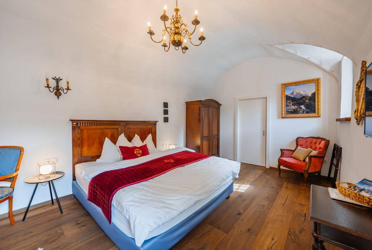 Schlafzimmer mit Holzbett, Holzboden, Gewölbedecke und traditioneller Einrichtung.