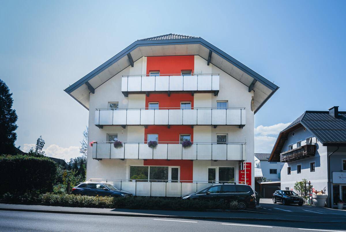 Frontansicht des Wohnhauses mit mehreren Balkonen und moderner Architektur unter blauem Himmel.
