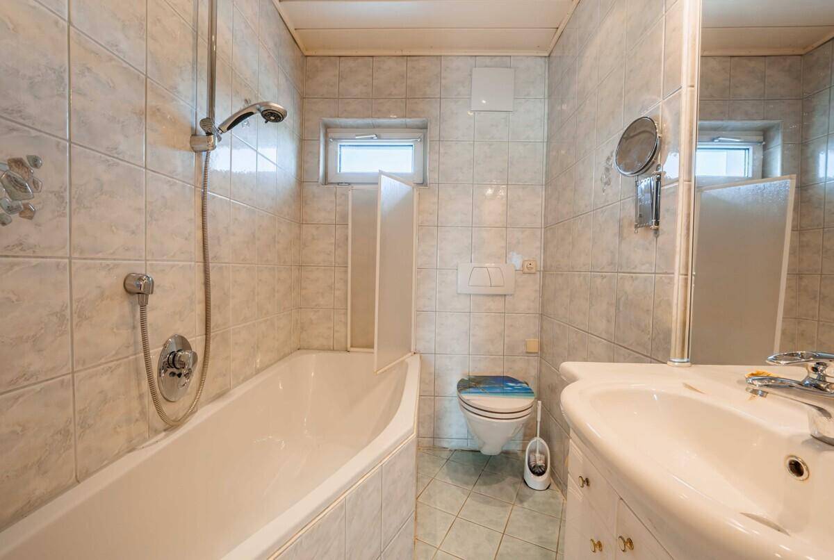 Dachgeschoss-Badezimmer mit Badewanne, WC, Waschbecken und hellen Fliesen.
