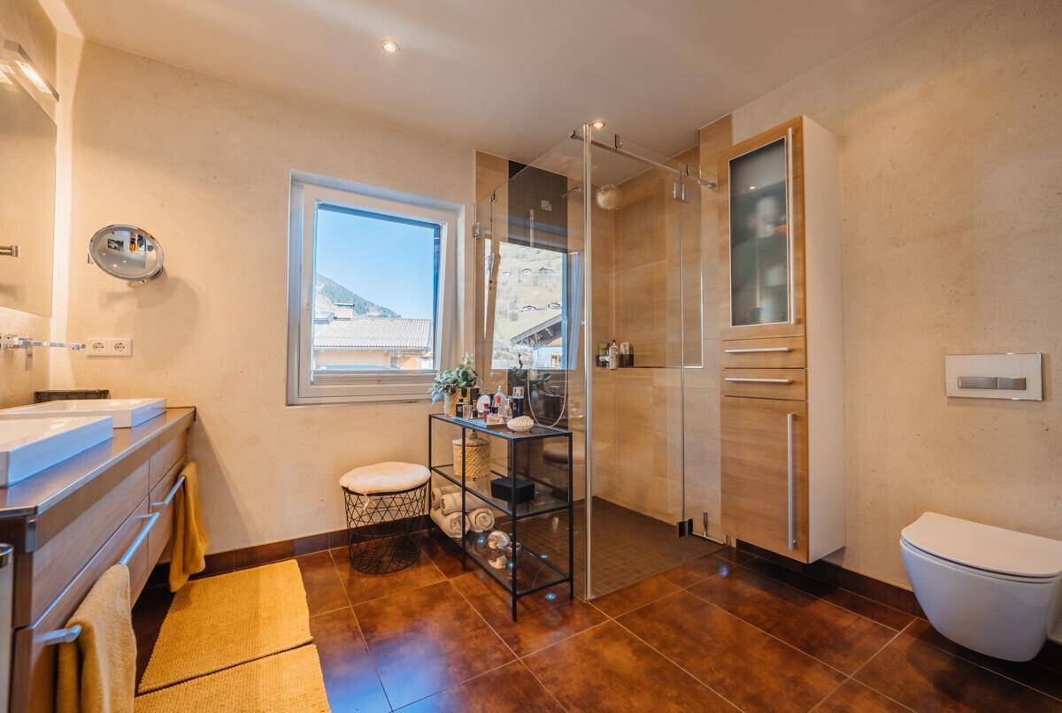 Modernes Badezimmer mit zwei Waschbecken, großer Dusche und Fenster mit Bergblick.