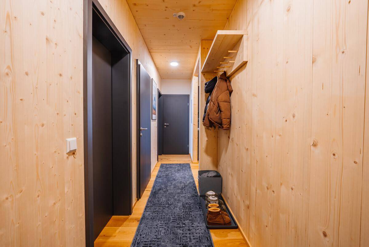 Heller Flur mit Holzvertäfelung und praktischer Garderobe, der zu den Zimmern führt.