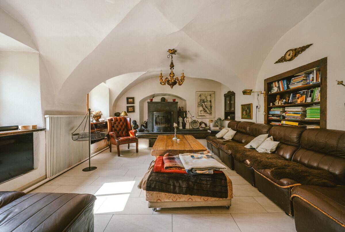 Großzügiges Wohnzimmer mit elegantem Kreuzgewölbe, Kamin und bequemen Ledersofas.