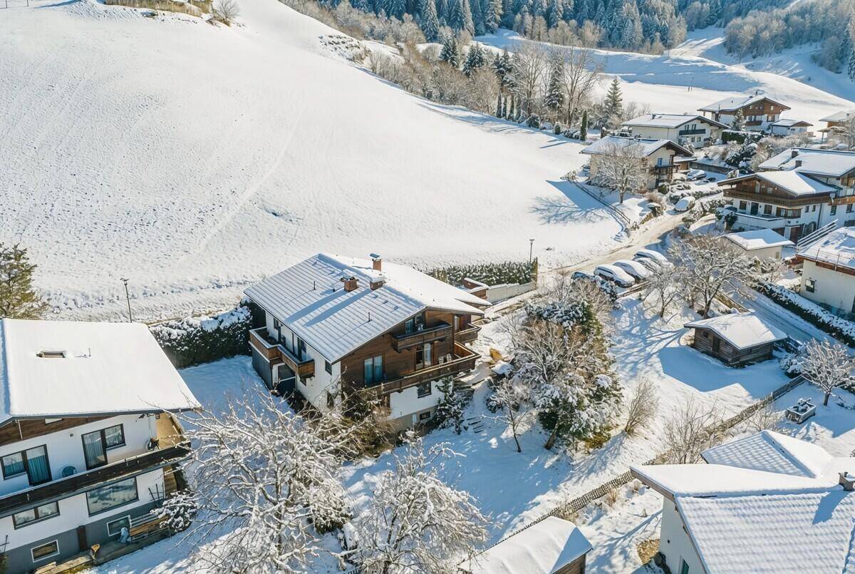 Winterliche Luftaufnahme des Anwesens, umgeben von verschneiten Hügeln und Bäumen.