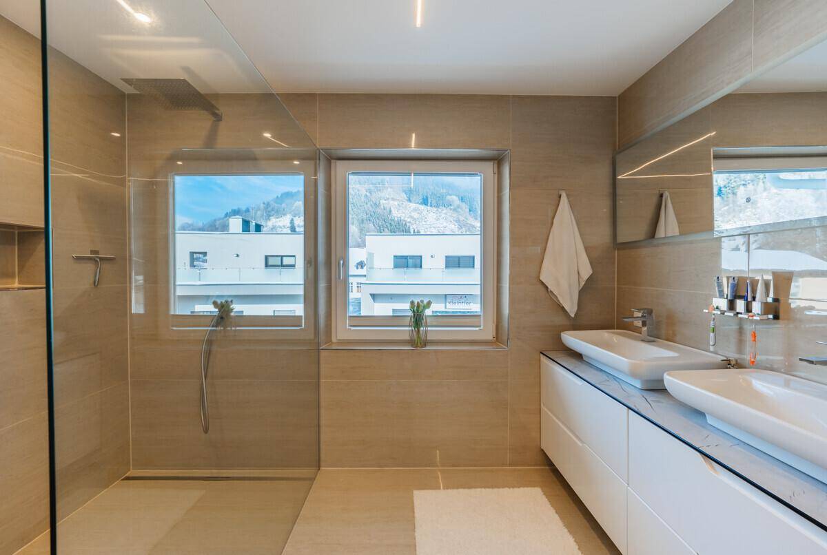 Modernes Badezimmer mit begehbarer Dusche, Doppelwaschbecken und Fenster mit Bergblick.