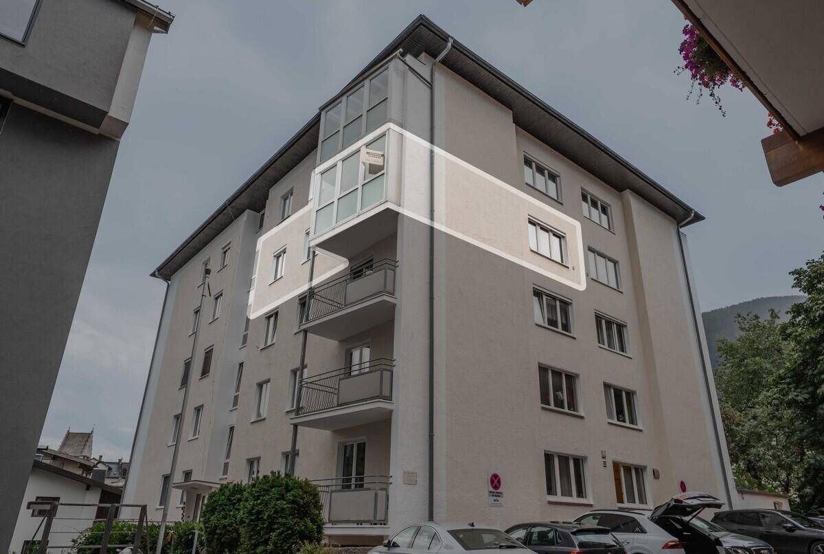 Ansicht des Mehrfamilienhauses mit hervorgehobenen Balkonen und Fenstern unter bewölktem Himmel.