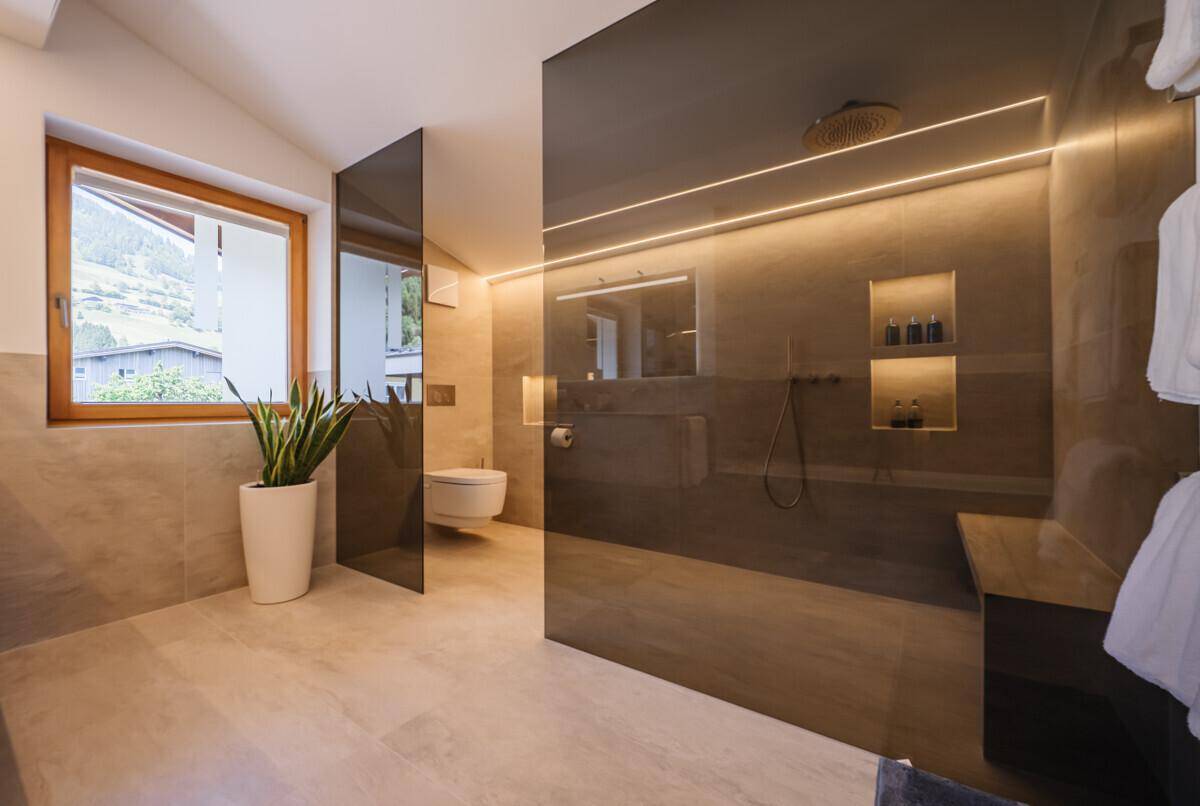 Elegantes Badezimmer mit begehbarer Dusche, Wand-WC und indirekter Beleuchtung.