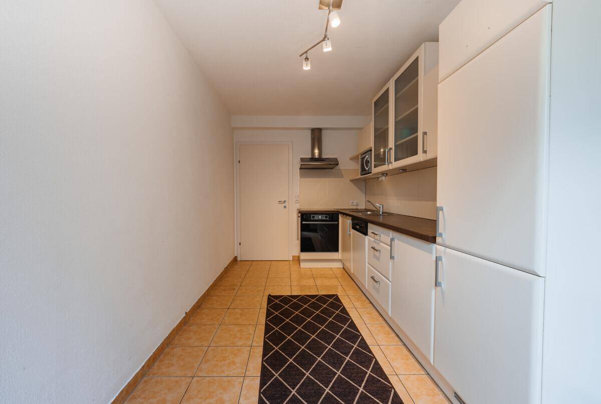 Kompakte Küche mit Einbauschränken, Backofen und Kühlschrank, praktisch eingerichtet.