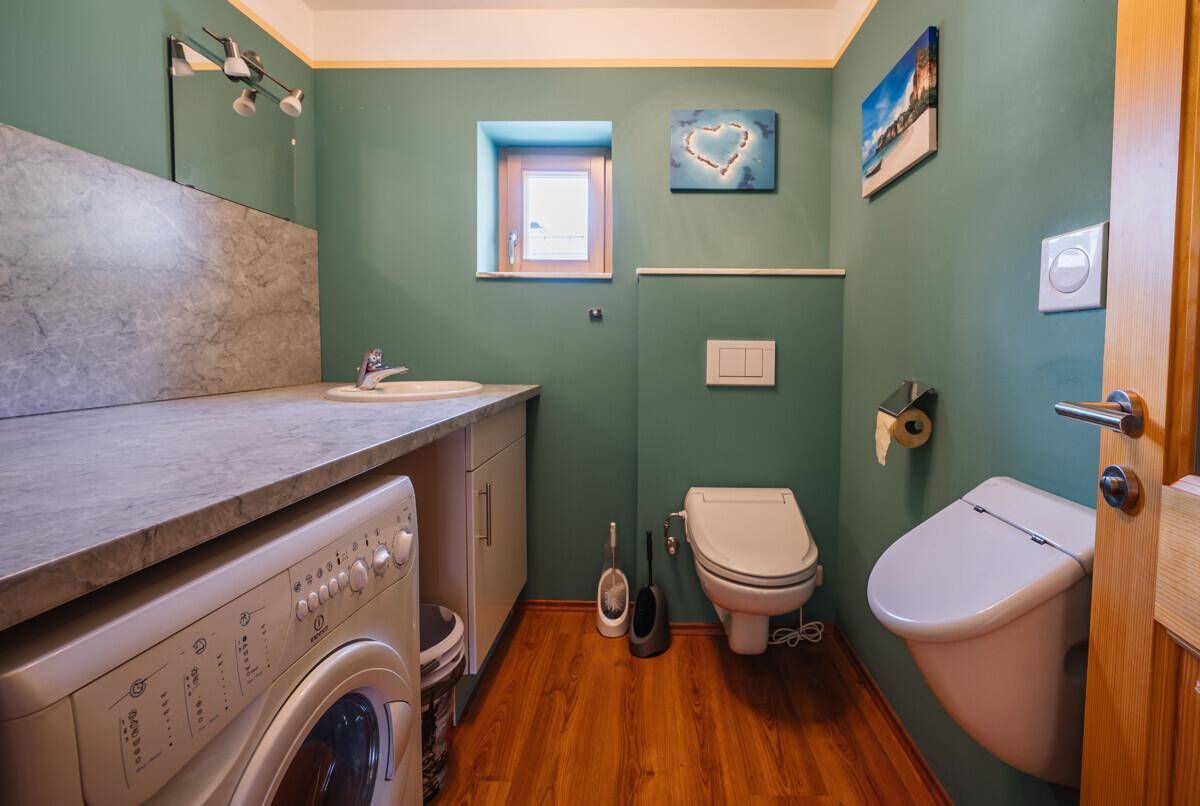Praktisches WC mit Waschmaschine, Waschbecken und Bidet, in einem frischen Grünton gestaltet.