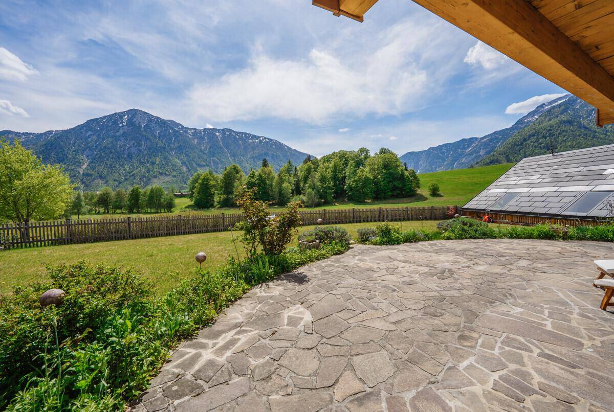 Weitläufige Steinterrasse mit freiem Blick auf grüne Wiesen und majestätische Berge.