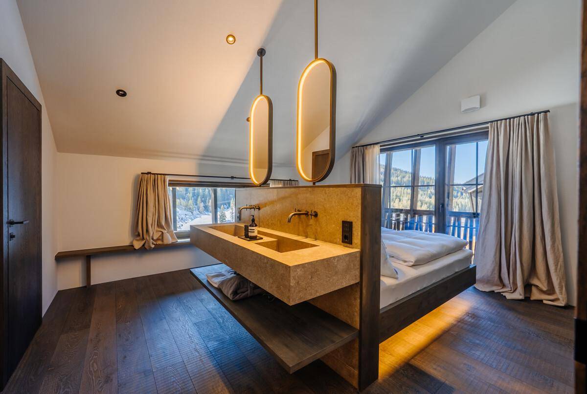 Modernes Schlafzimmer mit Holzboden, integriertem Waschbecken und Blick auf die Berge.
