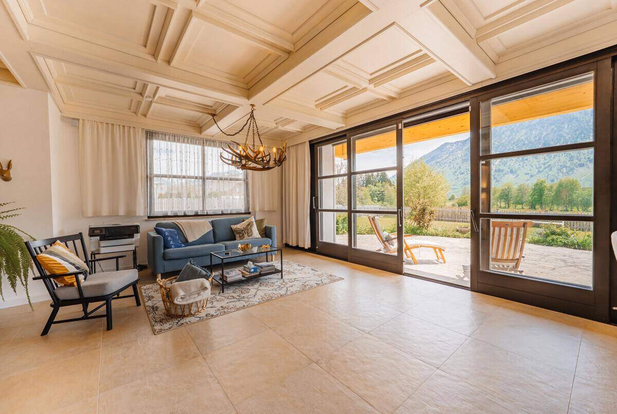 Gemütlicher Wohnbereich mit Sofa, Couchtisch und Zugang zur sonnigen Terrasse mit Bergblick.