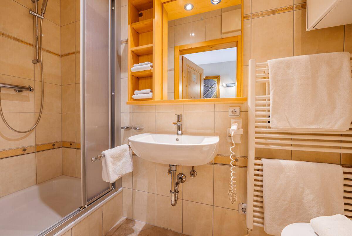 Funktionales Badezimmer mit Duschkabine, Waschbecken und beheiztem Handtuchhalter.