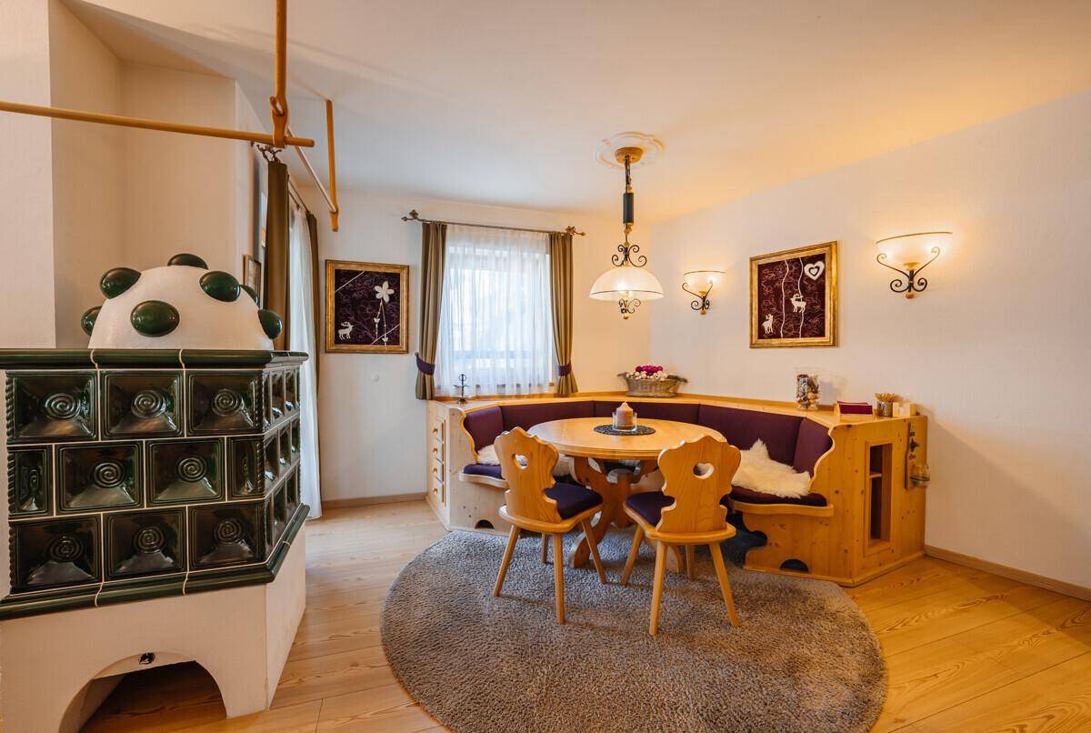 Gemütlicher Essbereich mit traditioneller Eckbank, Holztisch und Kachelofen.