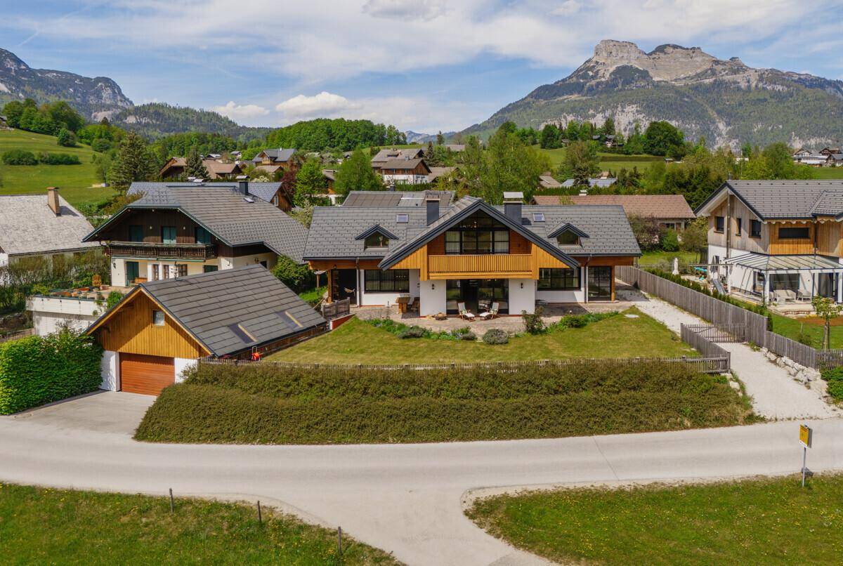 Attraktives Wohnhaus mit moderner Architektur und weitläufigem Grundstück vor alpiner Kulisse.