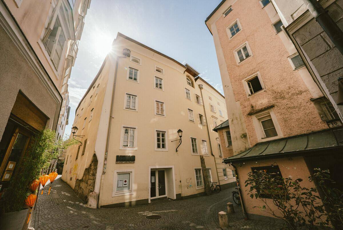 Historisches Gebäude in einer engen Gasse mit traditioneller Architektur und sonnigem Ambiente.
