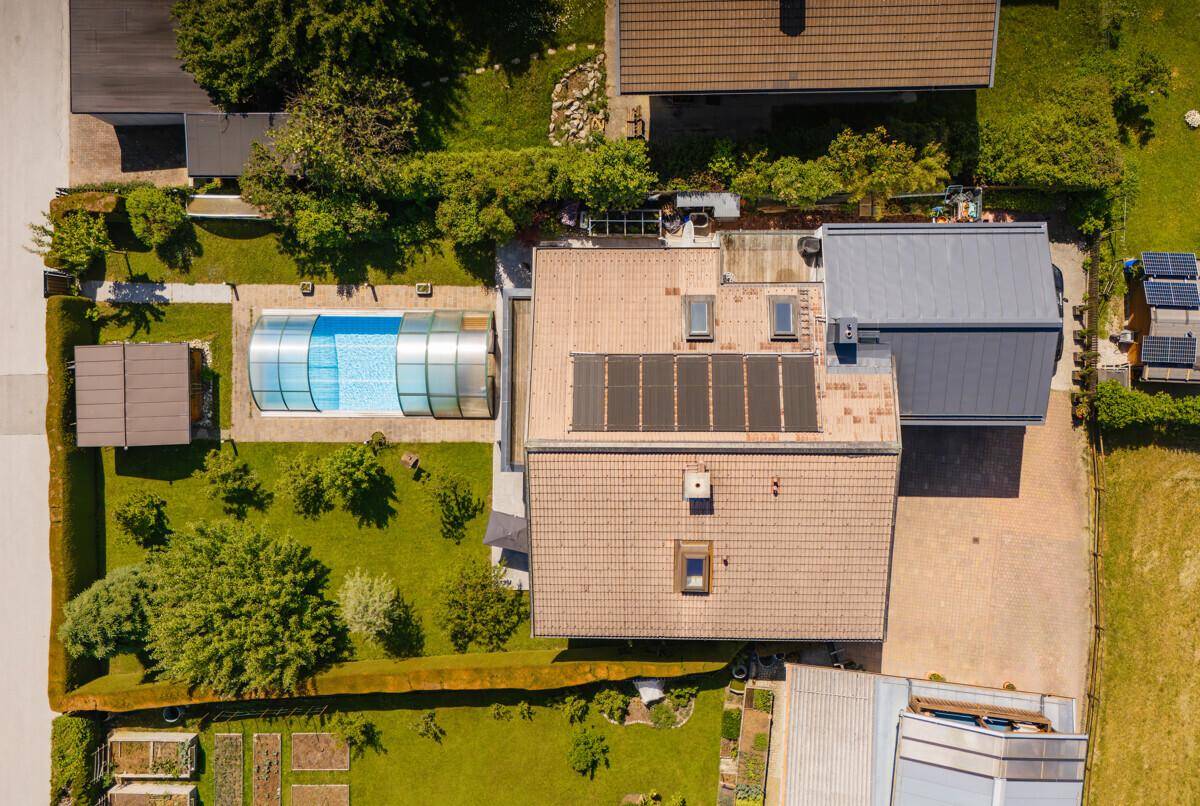 Vogelperspektive eines Anwesens mit Wohnhaus, Garten, Pool und Solaranlage auf dem Dach.