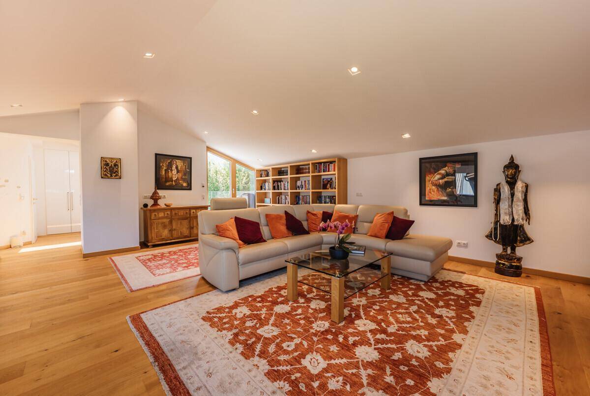 Helles Wohnzimmer mit großem Ecksofa, Holzboden und orientalischen Teppichen.