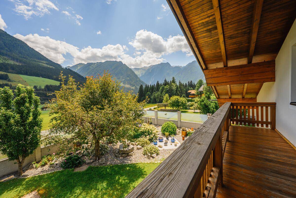 Geräumiger Holzbalkon mit Panoramablick auf die umliegende Berglandschaft und das Tal.