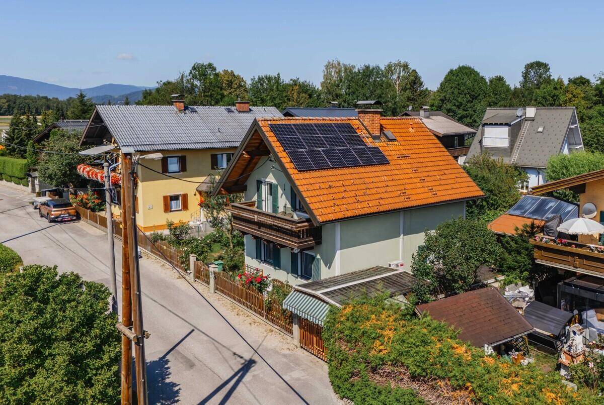 Vogelperspektive eines Wohnhauses mit Solarpaneelen auf dem Dach und angrenzender Straße.