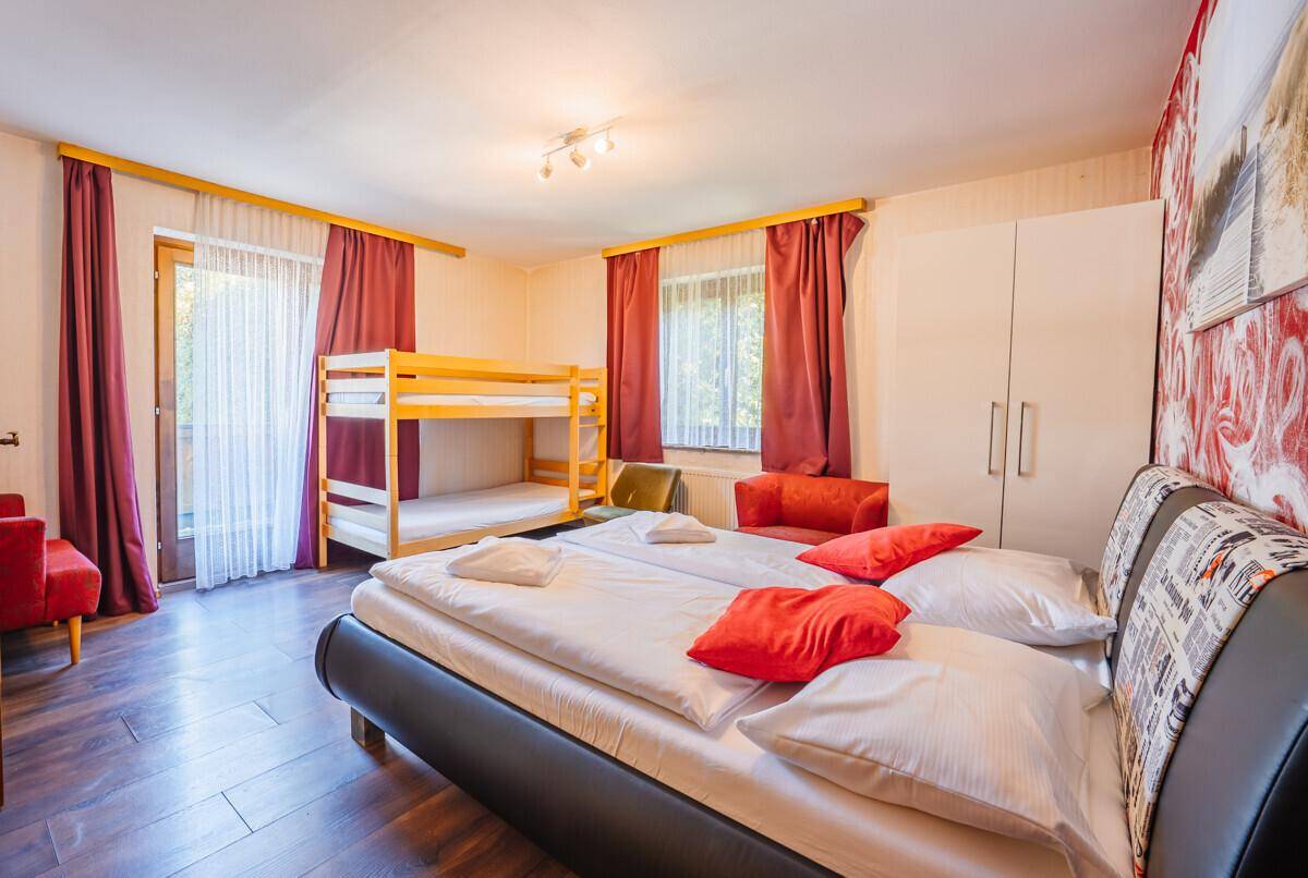 Geräumiges Schlafzimmer mit Doppelbett, Etagenbett und farbenfroher Dekoration.