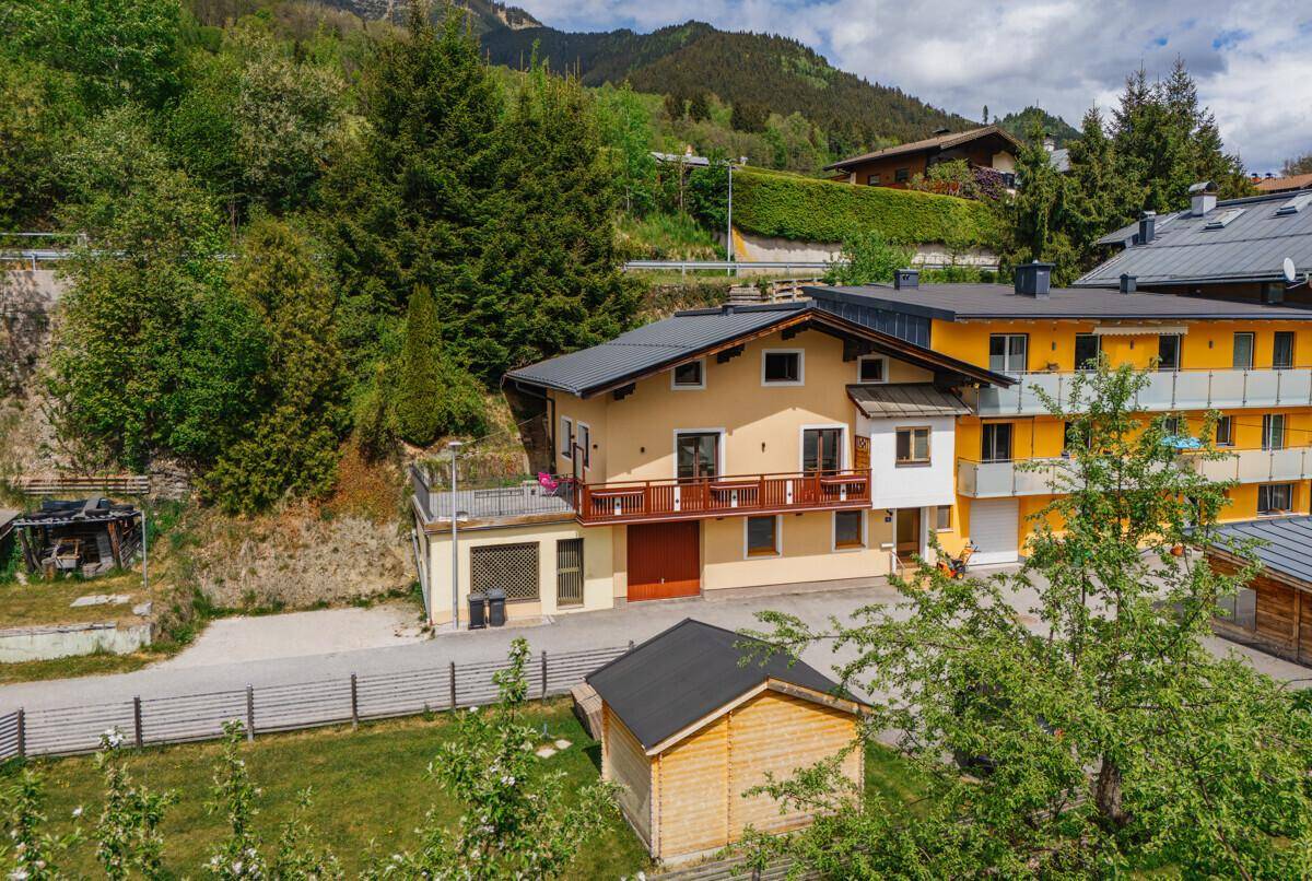 Luftaufnahme des Hauses mit Garten, umgeben von grünen Hügeln und Bergen.