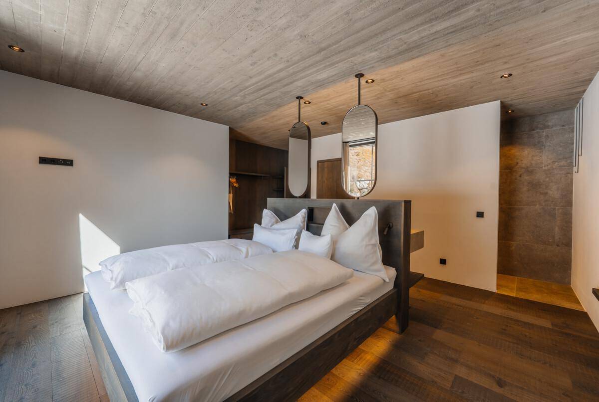 Helles Schlafzimmer mit Holzboden, bequemen Doppelbett und Blick auf die verschneite Landschaft.