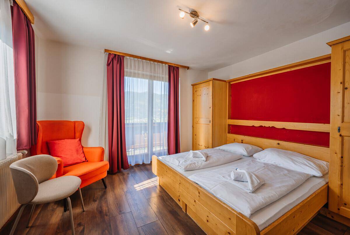 Helles Schlafzimmer mit Doppelbett, Holzmöbeln und direktem Zugang zu einem Balkon.