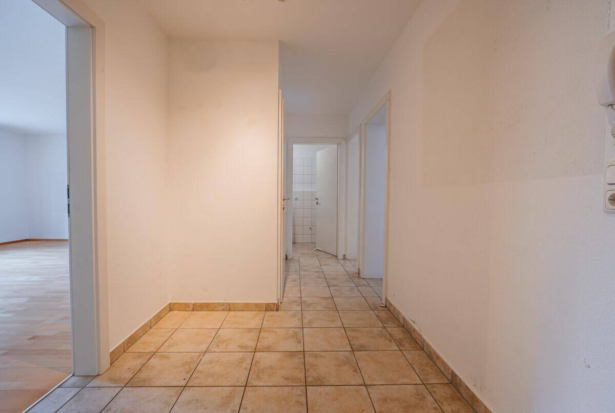 Heller Flur mit Fliesenboden, der zu verschiedenen Räumen der Wohnung führt.