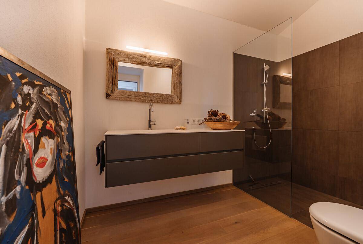 Modernes Badezimmer mit begehbarer Dusche, schwebendem Waschtisch und Holzelementen, sehr stilvoll.