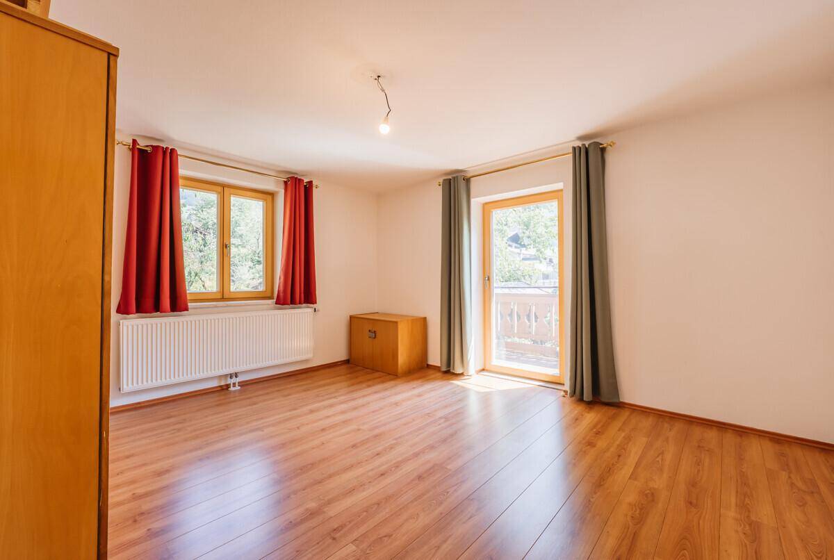 Helles Zimmer mit Holzboden und Zugang zu einem französischen Balkon, ideal als Schlafzimmer.
