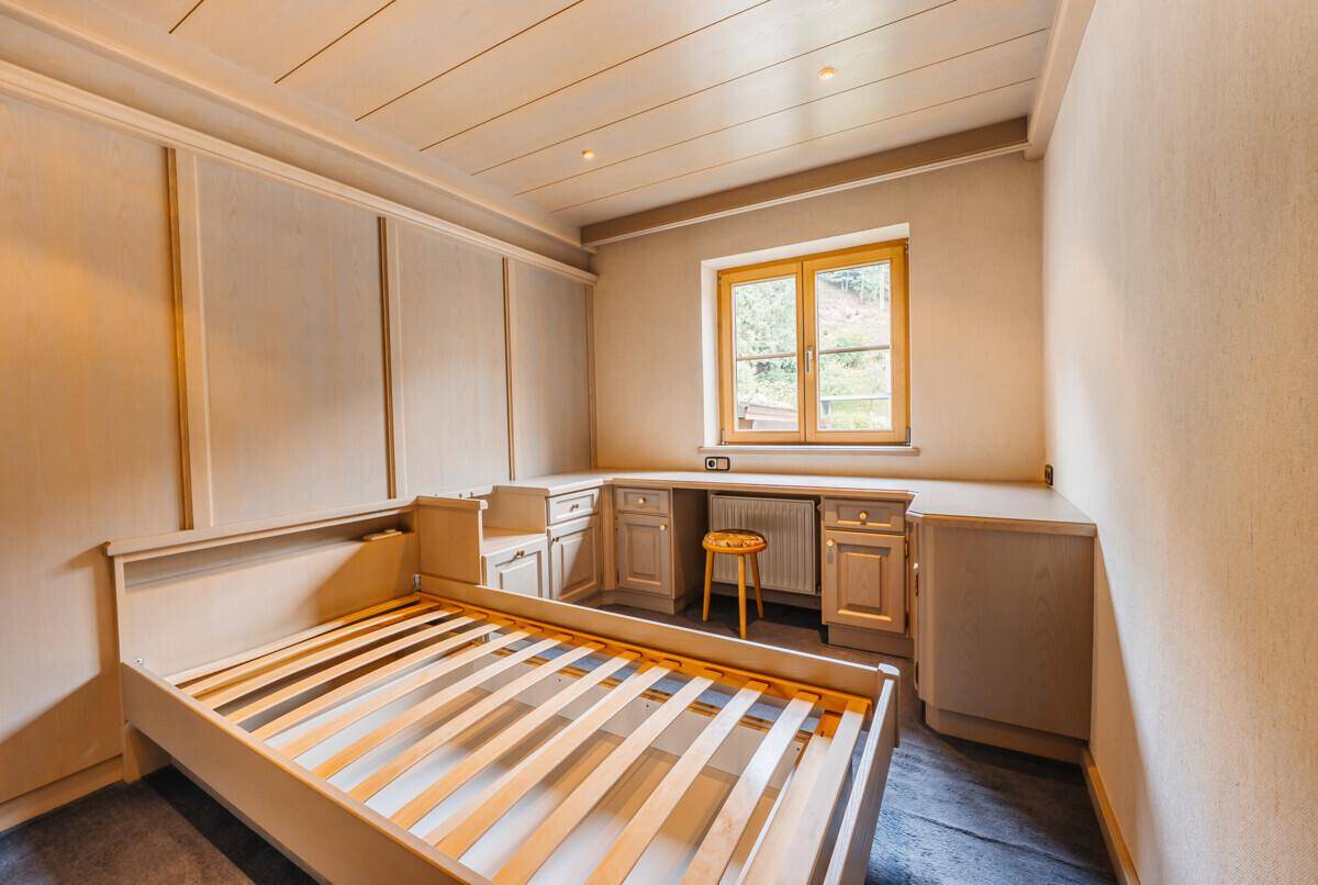 Schlafzimmer mit Bettrahmen, integriertem Schreibtisch und Stauraum, bietet praktischen Komfort.