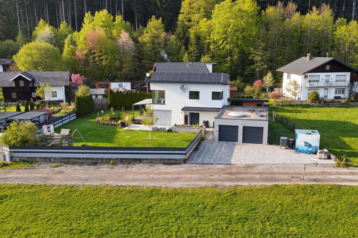 Luftaufnahme des modernen Hauses mit großem Garten, Doppelgarage und Photovoltaikanlage auf dem Dach.