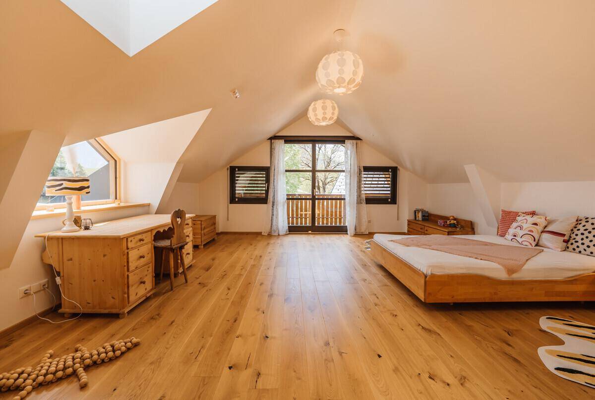 Geräumiges Kinderzimmer mit Holzboden, Schreibtisch und Zugang zu einem französischen Balkon.